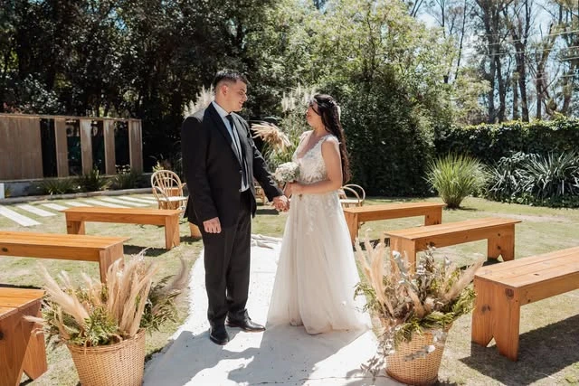 Boda celebrada en el jardín de La Quinta, junto a bancos de madera y árboles