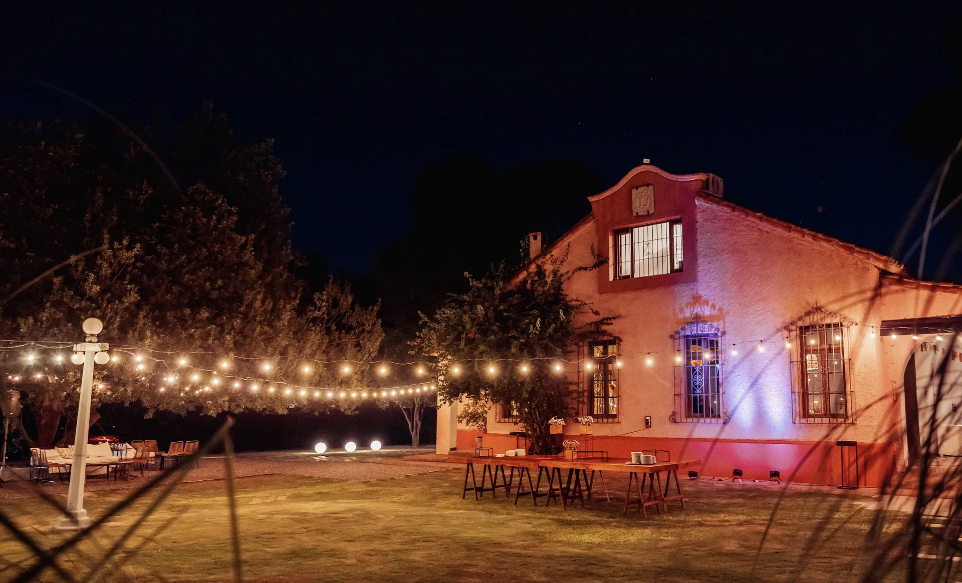 La casona de La Quinta iluminada, con mesas y guirnaldas de luces en el jardín