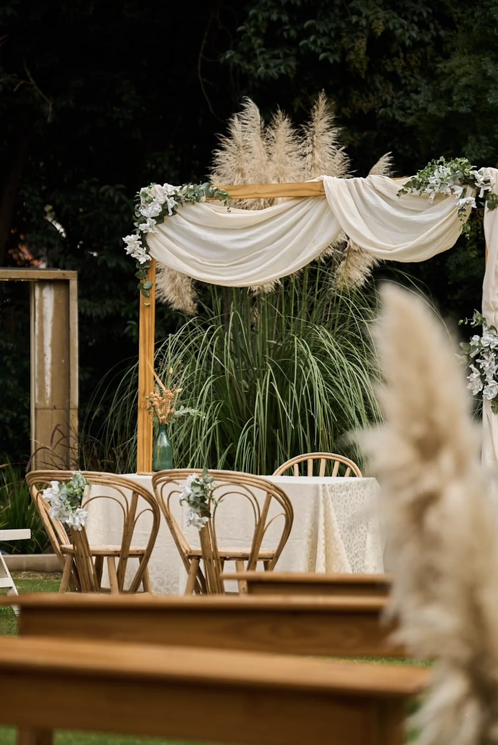Armado de ceremonia con telas claras y asientos junto a los árboles del jardín
