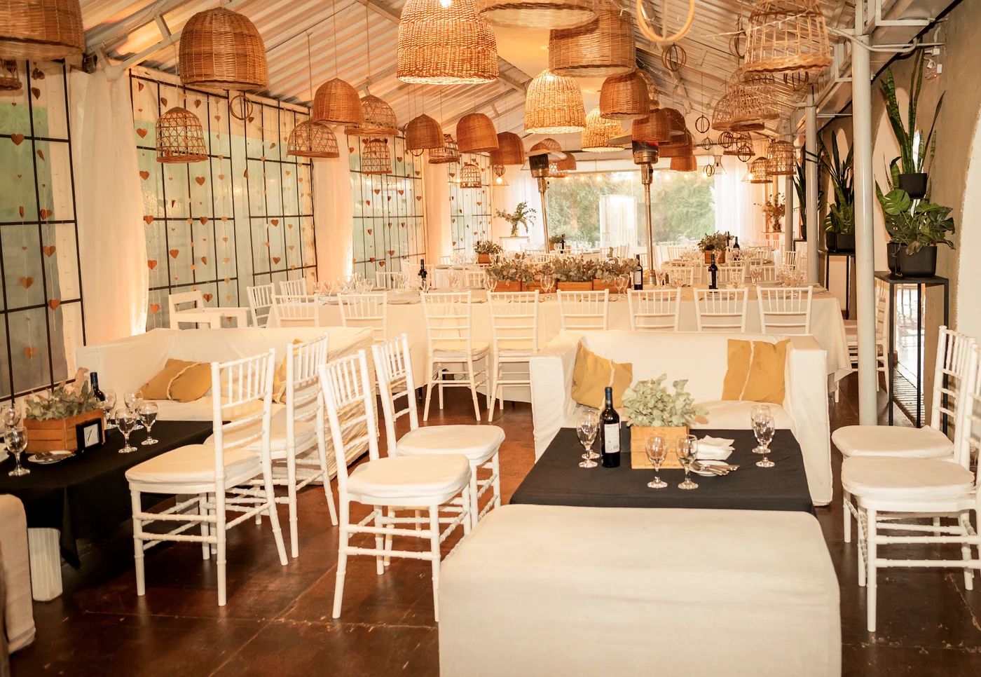 Interior del salón con sillas blancas, mesas preparadas y lámparas tejidas